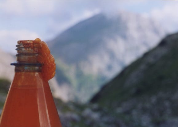 flasche uberschaumend vor bergen